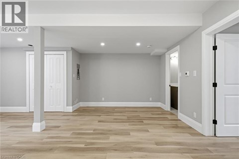 A realtor logo is on a wall in a room with wood flooring.