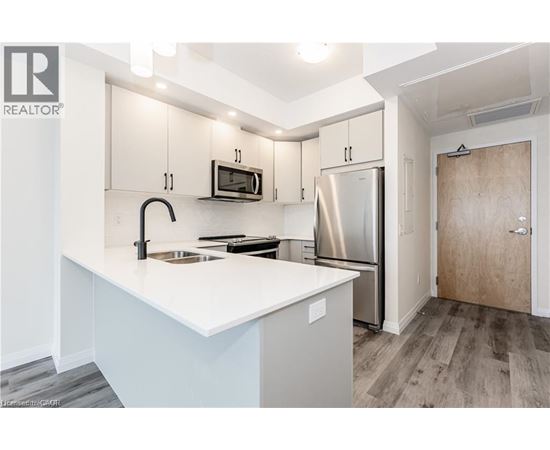 A kitchen with a white counter top and stainless steel appliances.