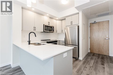 A kitchen with a white counter top and stainless steel appliances.