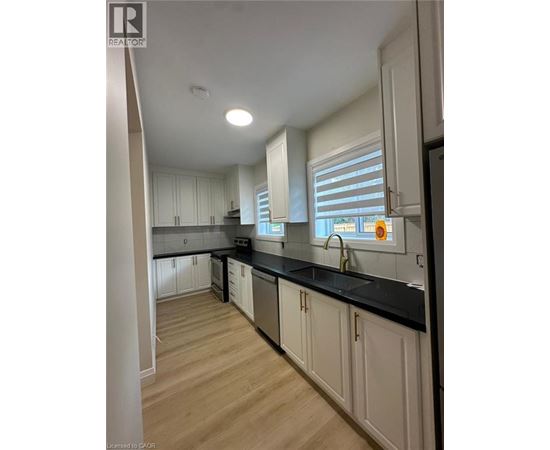 A kitchen with white cabinets and black countertops.