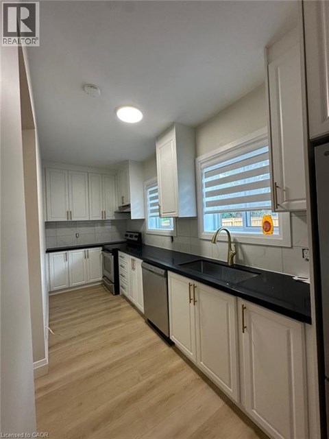 A kitchen with white cabinets and black countertops.