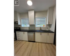 A kitchen with white cabinets and a black countertop.
