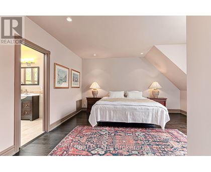A bedroom with a large bed and a rug on the floor.