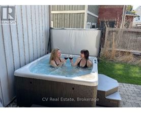 Two women are enjoying a hot tub in a backyard.