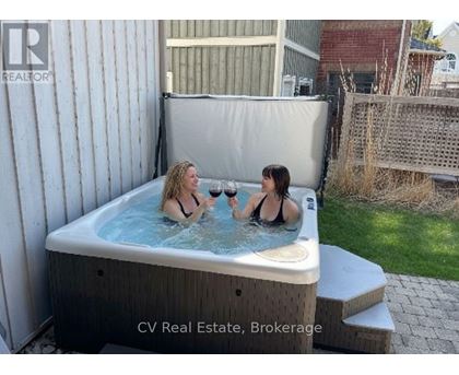 Two women are enjoying a hot tub in a backyard.