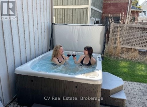 Two women are enjoying a hot tub in a backyard.