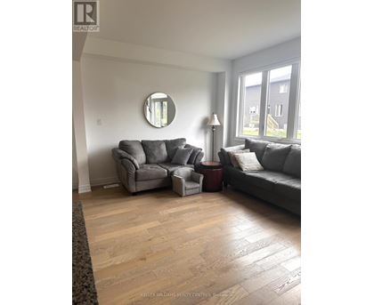 A living room with a grey couch and a round mirror on the wall.