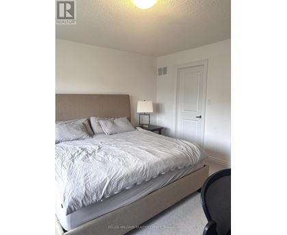 A bedroom with a bed, chair, and lamp.