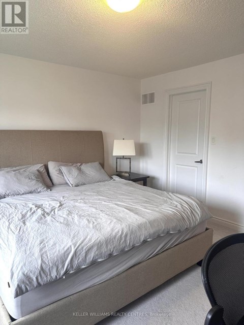 A bedroom with a bed, chair, and lamp.