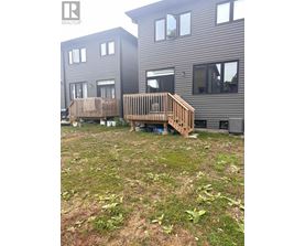 A wooden deck in front of a grey building.