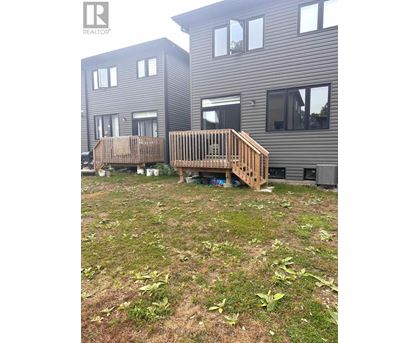 A wooden deck in front of a grey building.