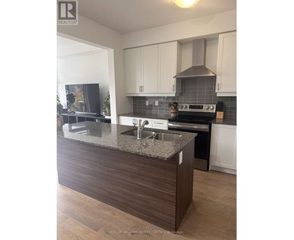 A modern kitchen with a granite countertop and stainless steel appliances.