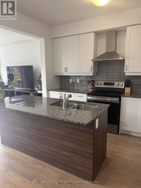 A modern kitchen with a granite countertop and stainless steel appliances.