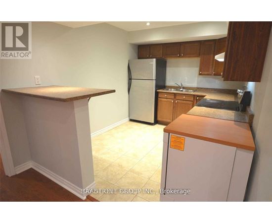A kitchen with a refrigerator, counter, and cabinets.