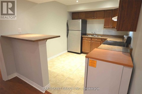 A kitchen with a refrigerator, counter, and cabinets.