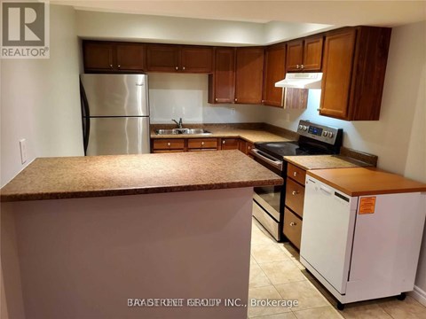 A kitchen with a refrigerator, stove, and cabinets.