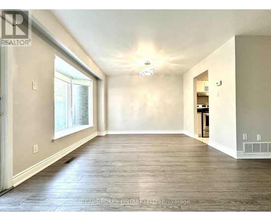 A spacious room with wood flooring and a ceiling light fixture.