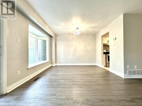 A spacious room with wood flooring and a ceiling light fixture.