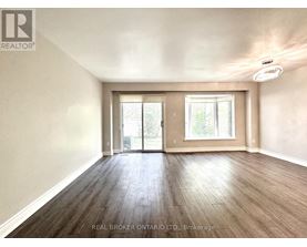 A spacious room with wood flooring and a sliding glass door.