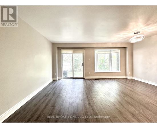 A spacious room with wood flooring and a sliding glass door.