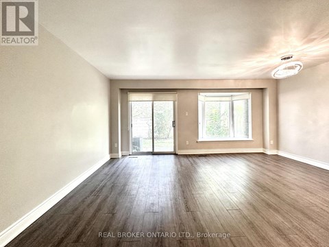 A spacious room with wood flooring and a sliding glass door.