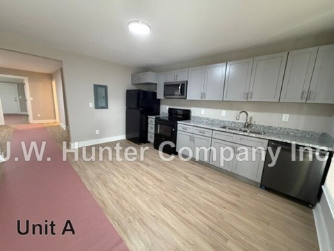 A kitchen with wooden floors and white cabinets.