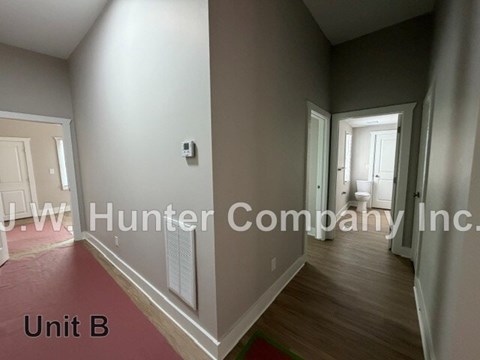 A hallway with a red carpet and white walls.