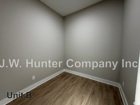 A room with wooden flooring and white walls, labeled as Unit B.