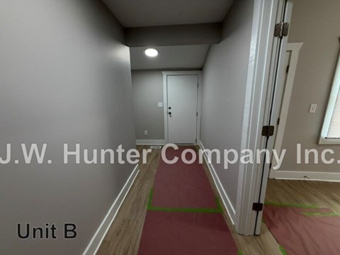 A hallway with a red carpet and white walls.