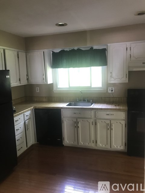 A kitchen with white cabinets and black appliances.