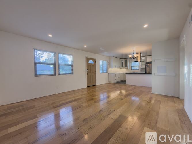 A spacious room with wooden flooring and a large window.