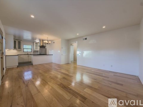 A spacious room with wooden flooring and white walls.