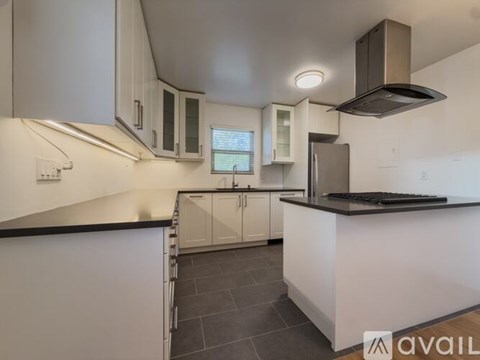 A modern kitchen with white cabinets and a black countertop.