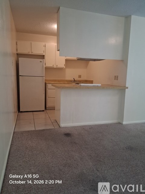 A kitchen with white cabinets and a white refrigerator.