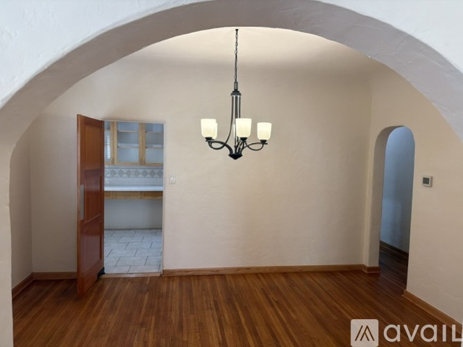 A room with wooden floors and a chandelier hanging from the ceiling.