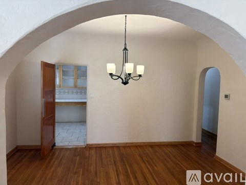 A room with wooden floors and a chandelier hanging from the ceiling.