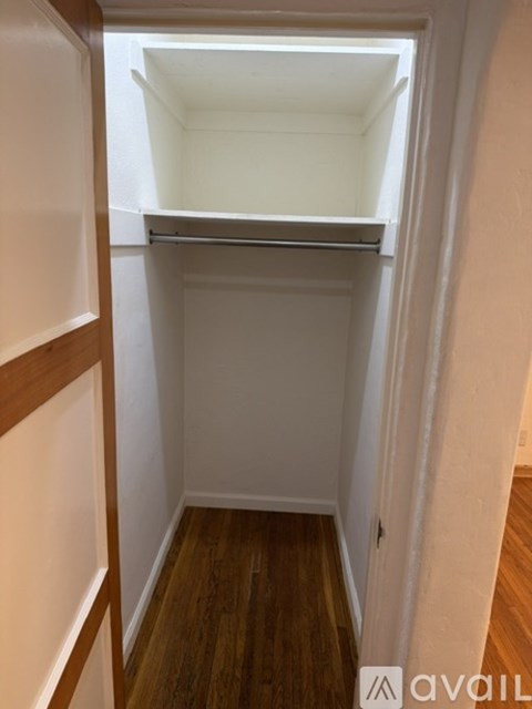 A small, empty room with a wooden floor and white walls.
