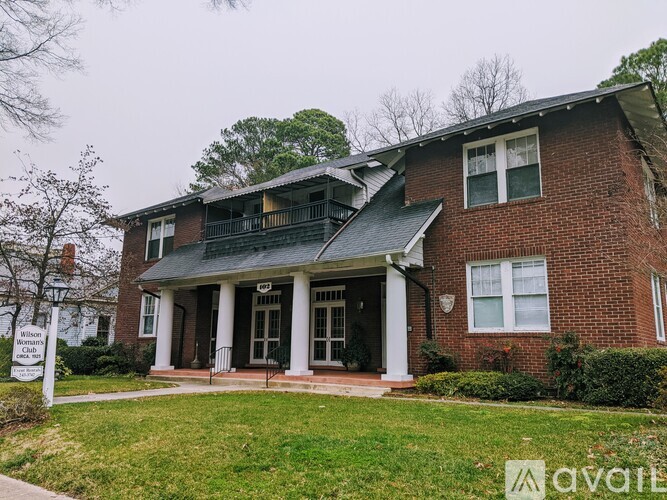 A brick house with a porch and a sign that says "Woman".