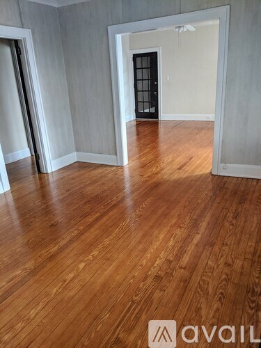 A room with wooden flooring and a door in the background.