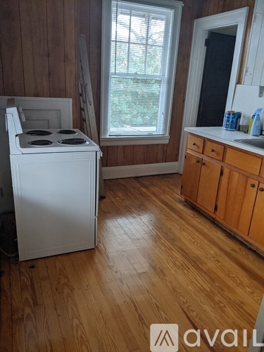 A white stove in a kitchen with wooden cabinets and a window.