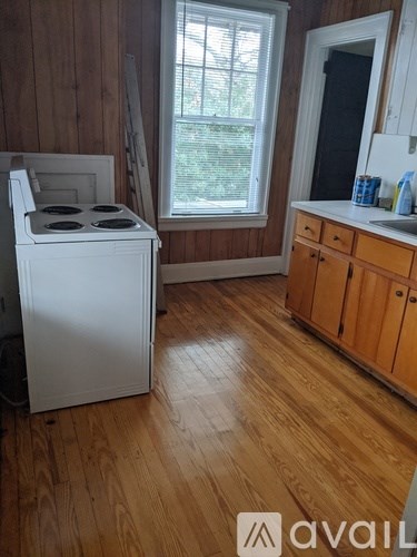 A white stove in a kitchen with wooden cabinets and a window.