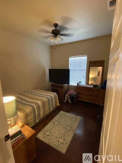 A bedroom with a bed, a dresser, and a ceiling fan.