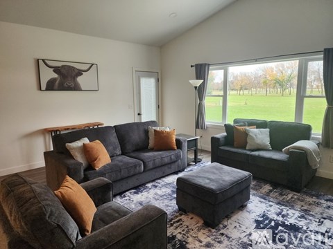 A living room with a grey couch and a brown ottoman.