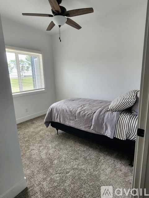 A bedroom with a bed, carpet, and a ceiling fan.