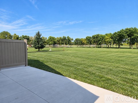 A large, open grassy field with a clear blue sky above.
