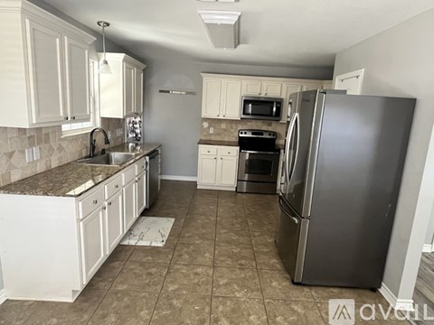A kitchen with white cabinets and a tile floor.