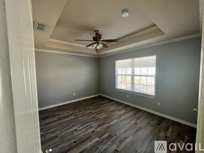 A room with a ceiling fan and a window with blinds.