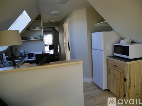 A kitchen with a white fridge and a microwave on top of it.