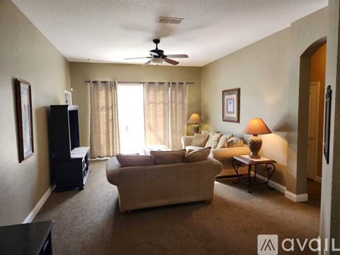 A living room with a couch, a chair, a coffee table, and a ceiling fan.