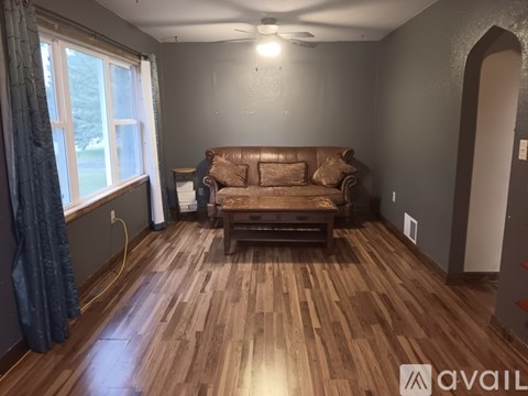 A living room with a brown couch and wooden floors.